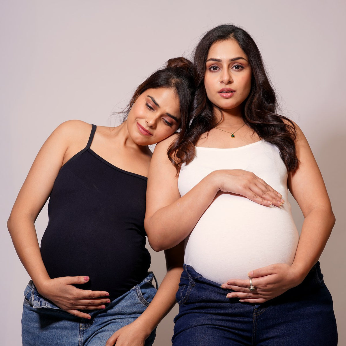 Two moms-to-be, one resting her head on the other's shoulder
